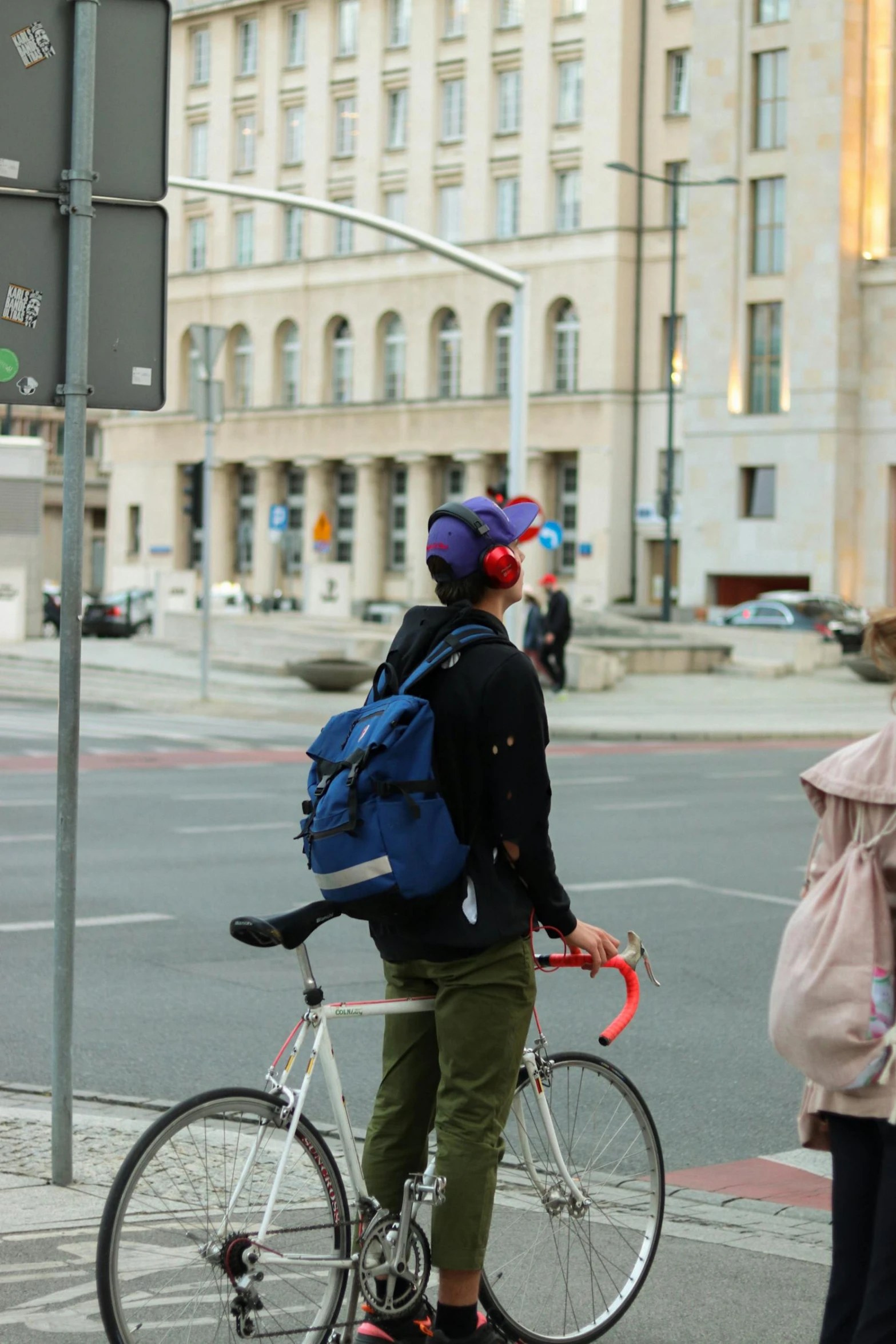 woman wearing a black jacket and purple beanie riding her bike down the street