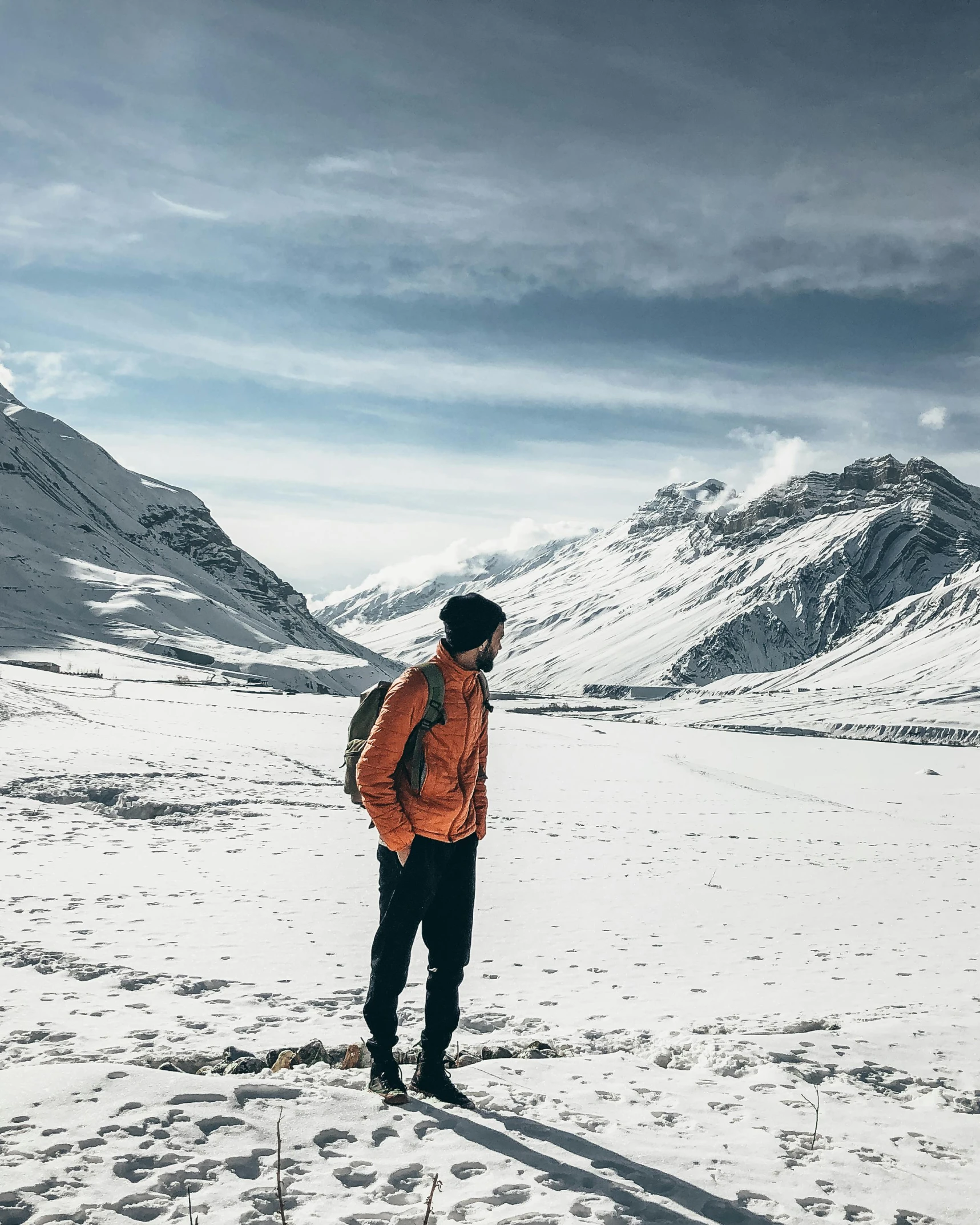 a person wearing an orange jacket stands in the snow