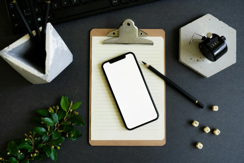 a phone on a clipboard next to a keyboard