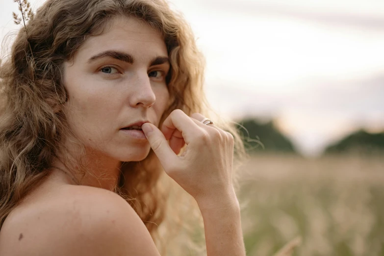 a woman with long hair standing in front of a field