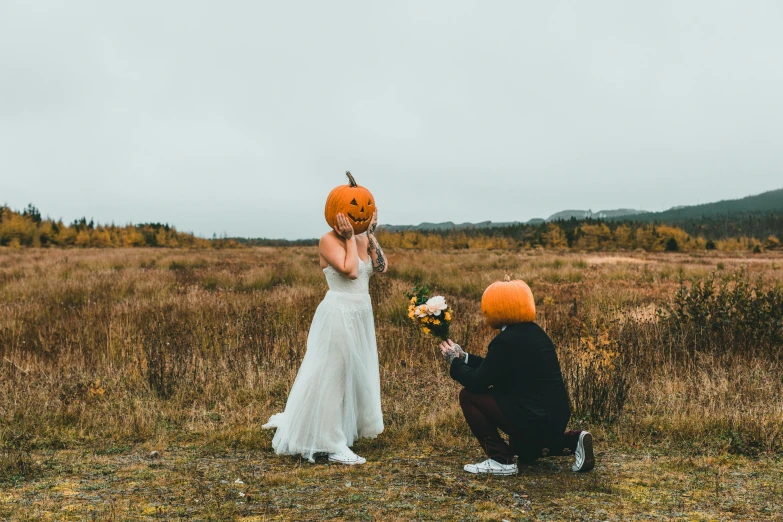 a person kneeling down holding a pumpkin in front of another person