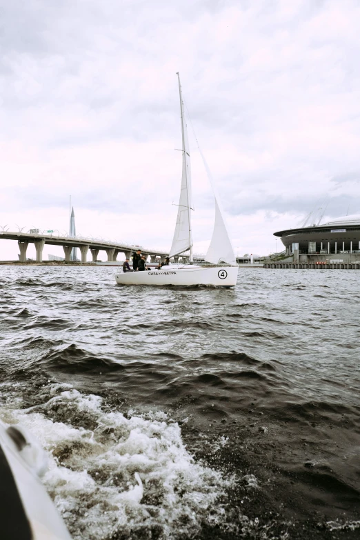 a sailboat sailing near an old bridge with a view of a city