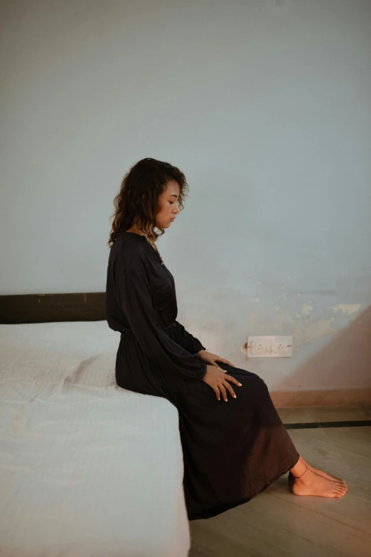 woman sitting on the edge of a mattress looking away