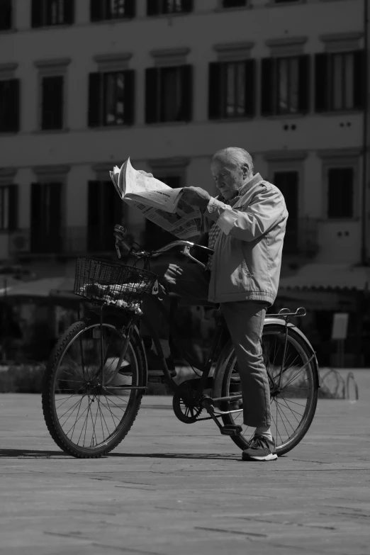 an older man with a bicycle reading newspaper