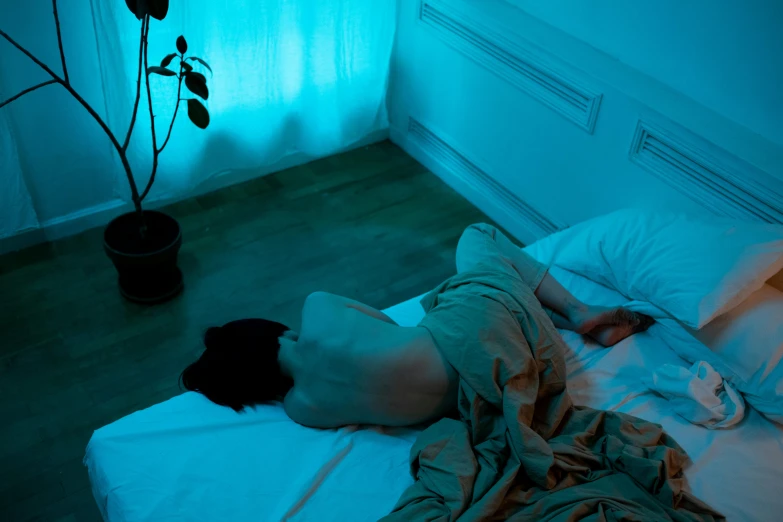 a person in a bed with dark light on the wall