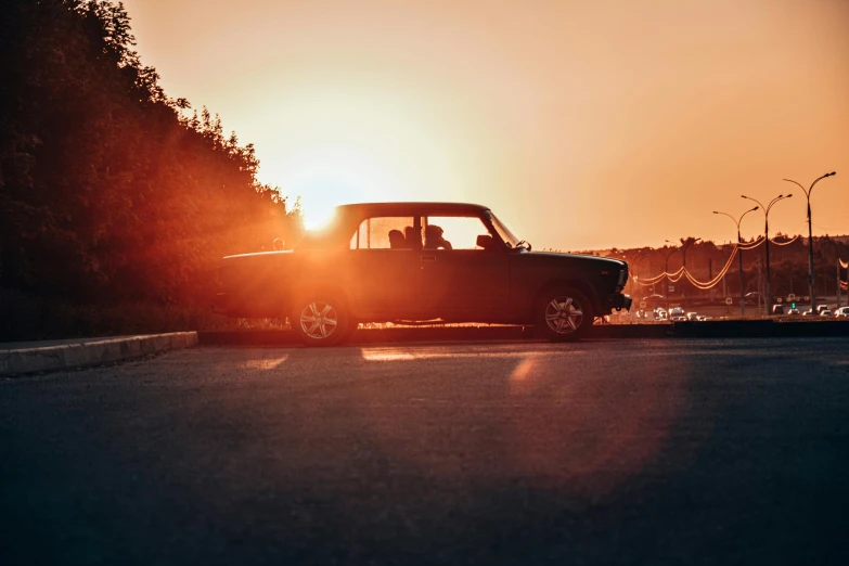 an old pickup truck driving down a road in the sunset