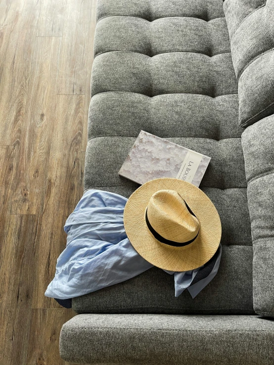 a tan hat lies on the seat of a gray couch