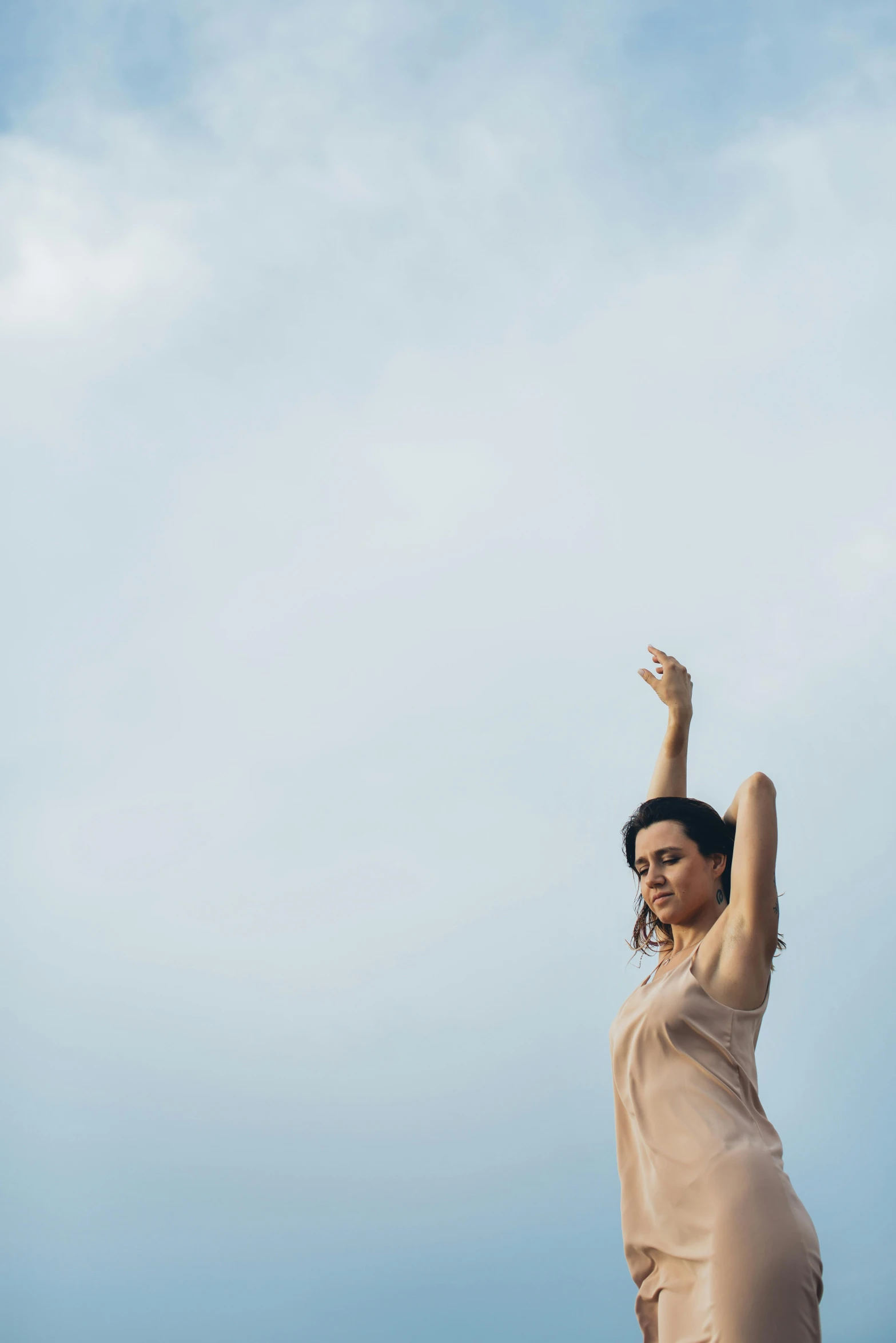 a woman wearing a dress flying a kite in a blue sky