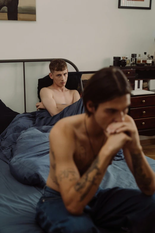 a couple of young men sitting next to each other in bed