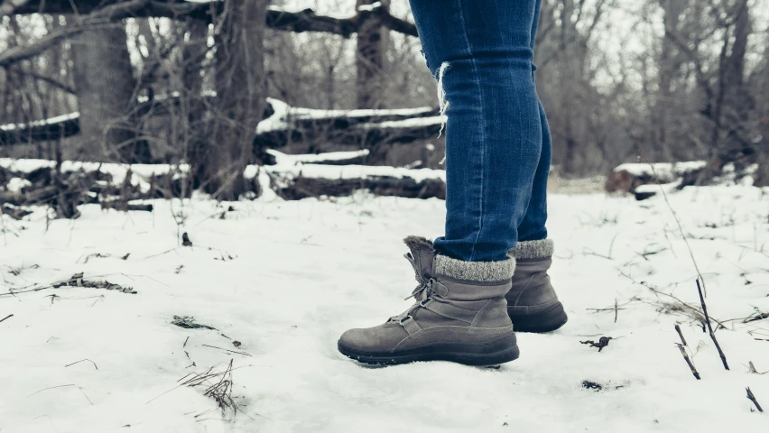 woman wearing warm shoes in the snow in front of an old wooden building