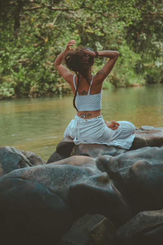 a woman is sitting on rocks near the water