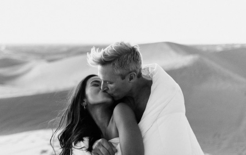 a man and woman kissing while wearing white dresses