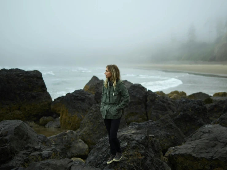 a woman stands on top of a large rock