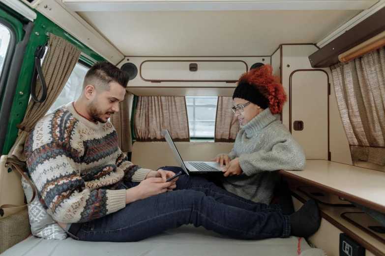 a young man is sitting on the seat of a bus with a laptop