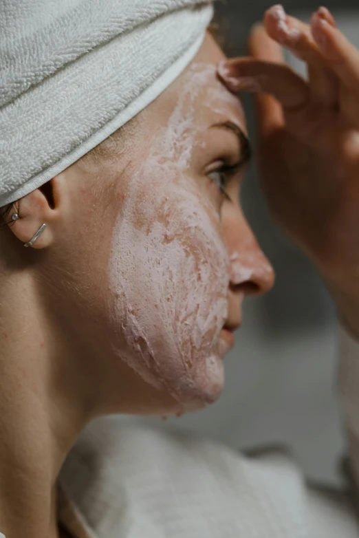 a woman with facial mask on standing near the mirror