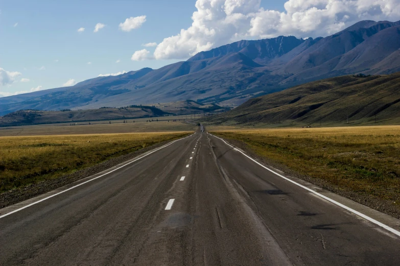 a road in the middle of nowhere with mountains behind it