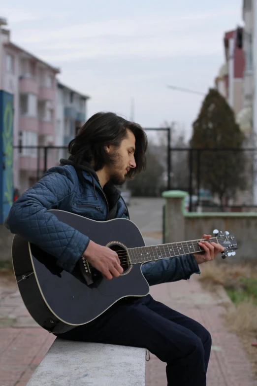 a man playing an acoustic guitar while sitting on a bench