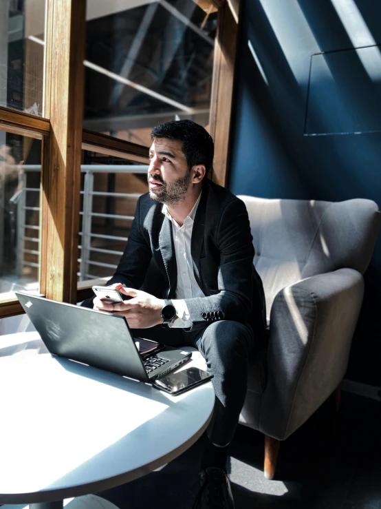 the man is sitting on a chair while working on his laptop