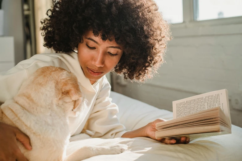 woman laying down reading a book while holding cat