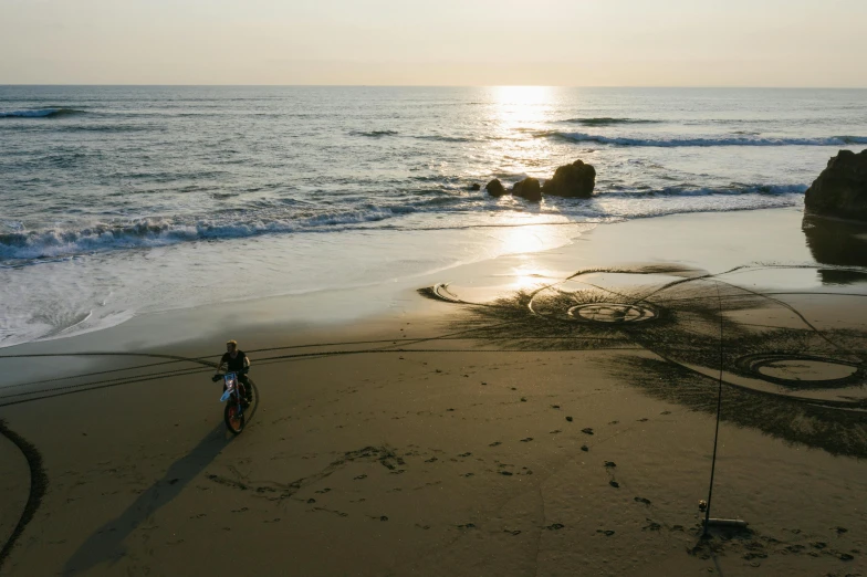 man riding bicycle near beach with the sun setting