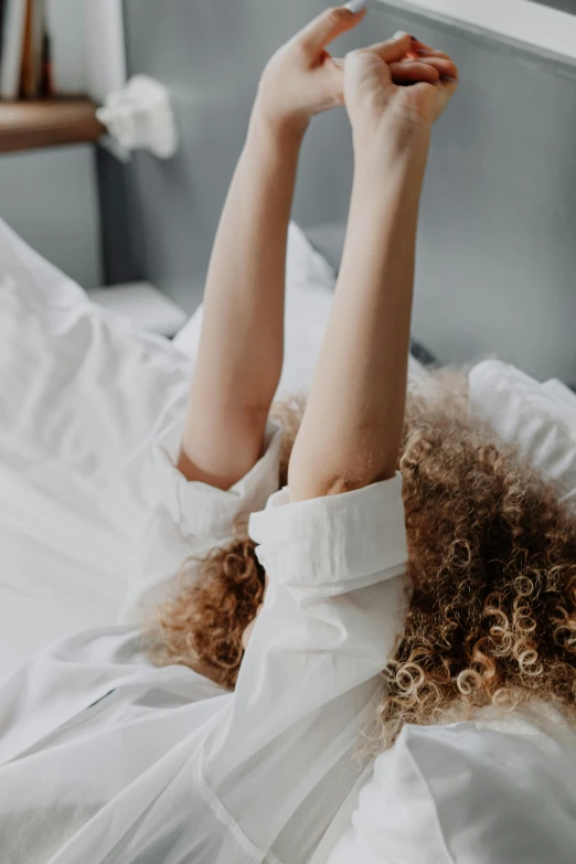 a woman laying in bed wearing a white dress