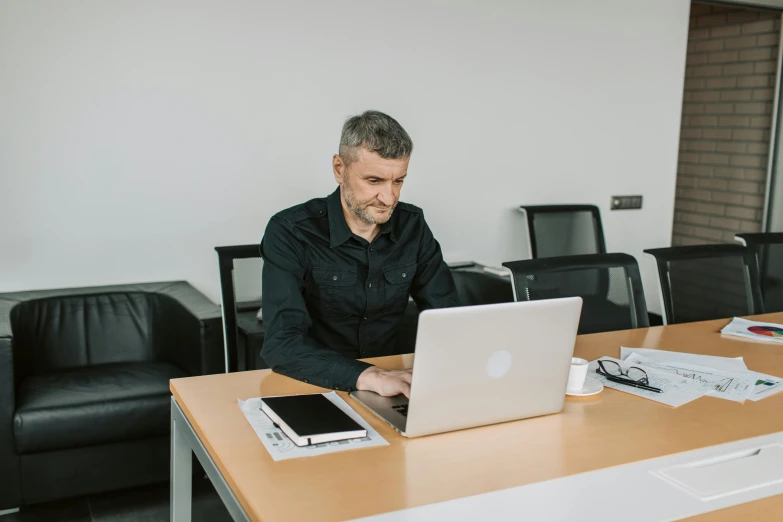 a man is looking at his macbook on the table