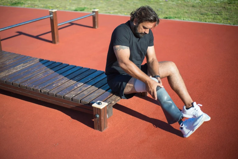 a man sits on a bench while he rests his shoe off