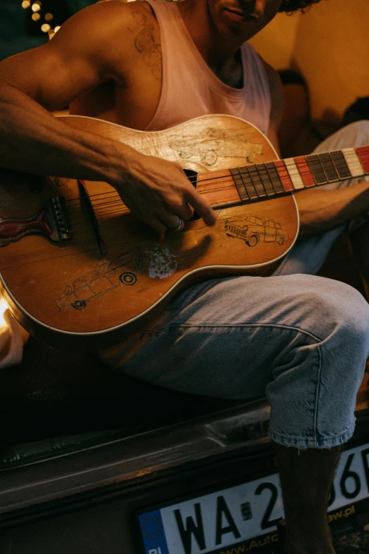 a man sitting in the back of a truck playing a guitar