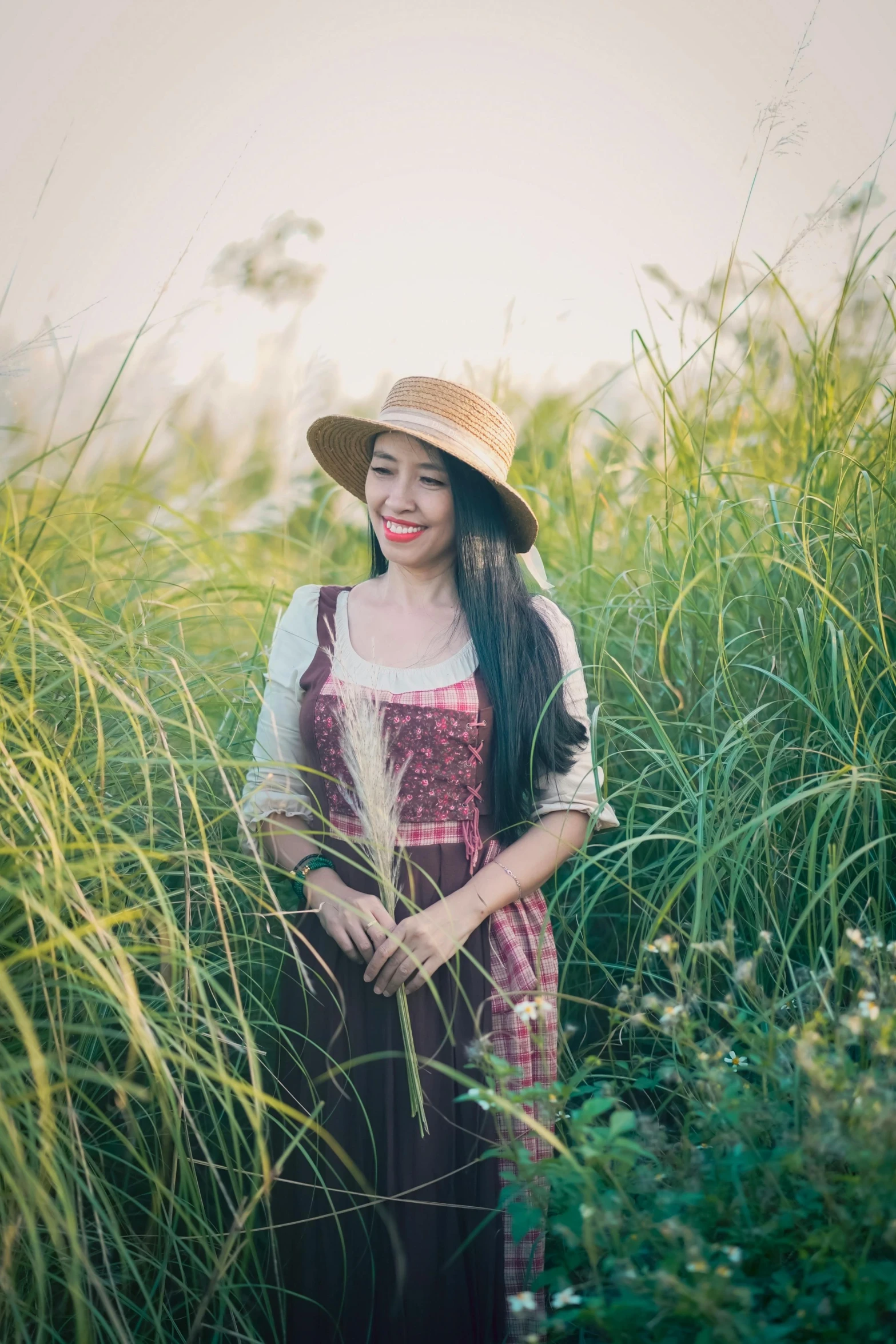 woman with long hair wearing a hat and dress in a grassy field