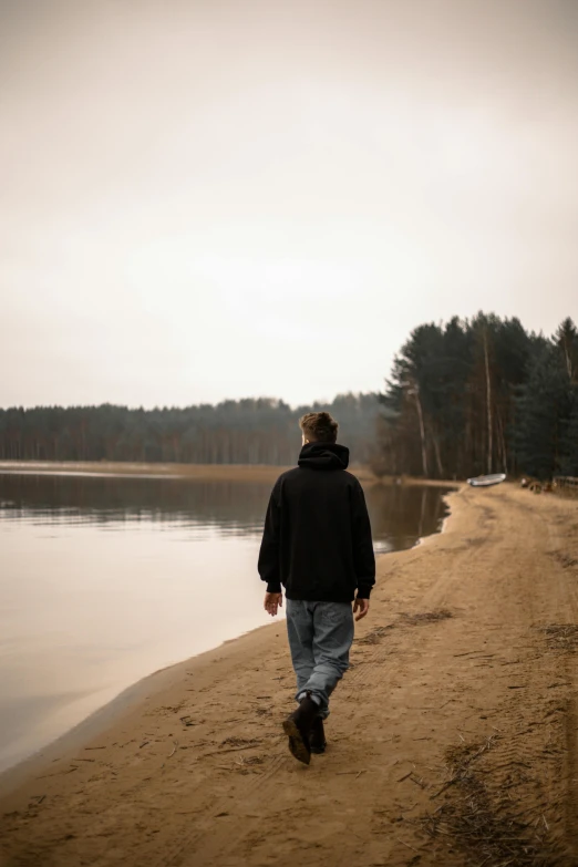 a man walking along a dirt path near a lake