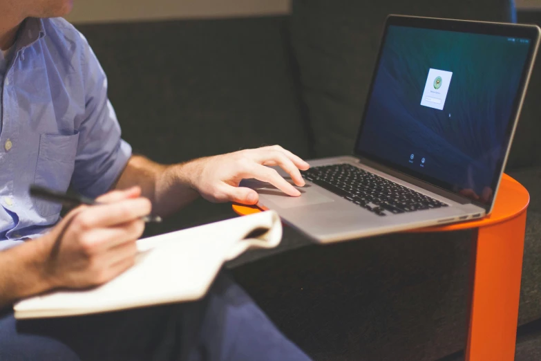 a person is writing on a laptop while sitting down