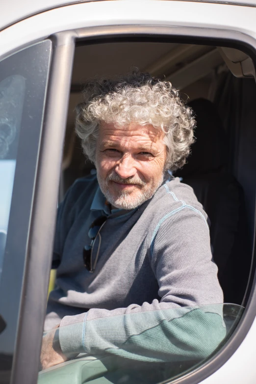 the older man is sitting inside of a truck looking out the window