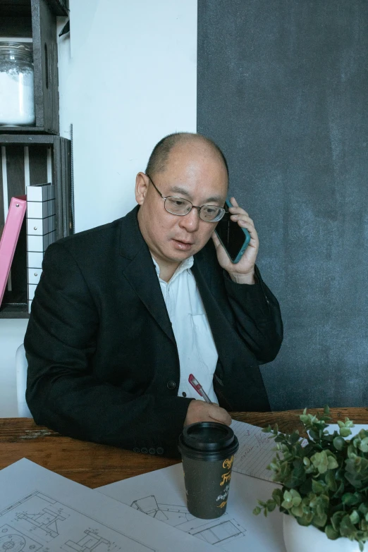 man in a business suit on the phone and a cup