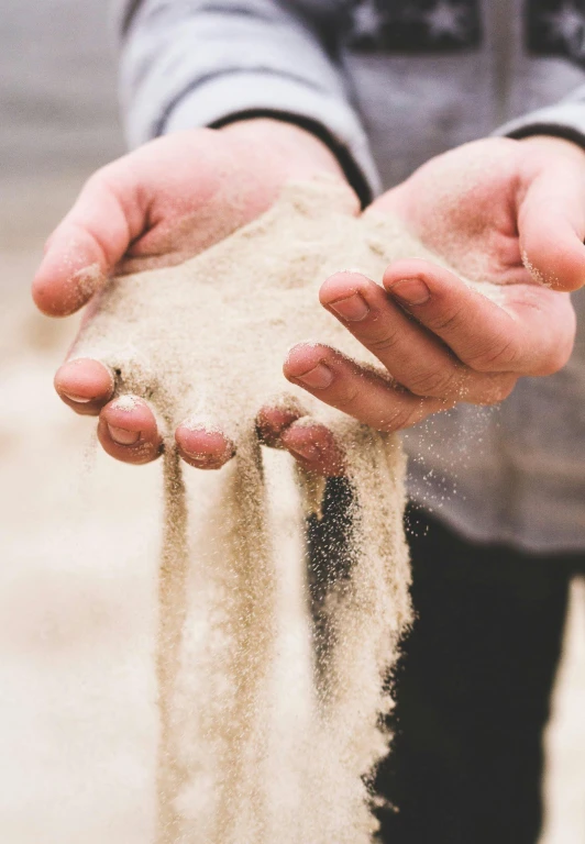 someone is holding sand in their hands and sprinkling with it