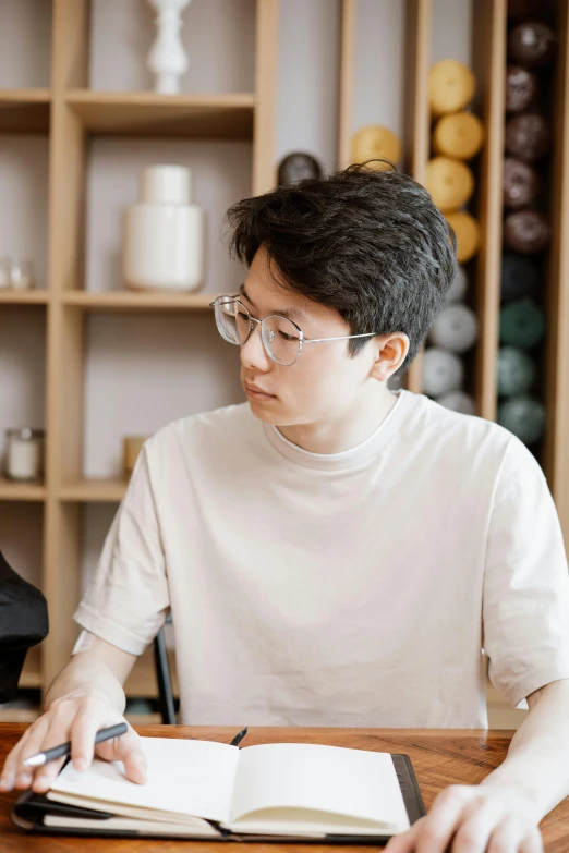 the young man is reading a book at his desk