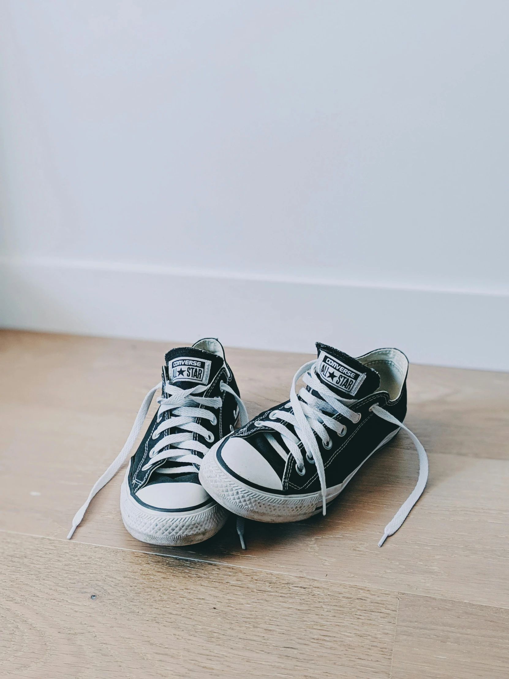 two black and white sneakers are sitting on the floor