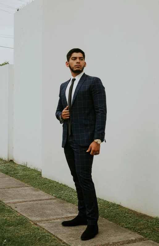 a man with a tie, suit and dress shoes standing outside