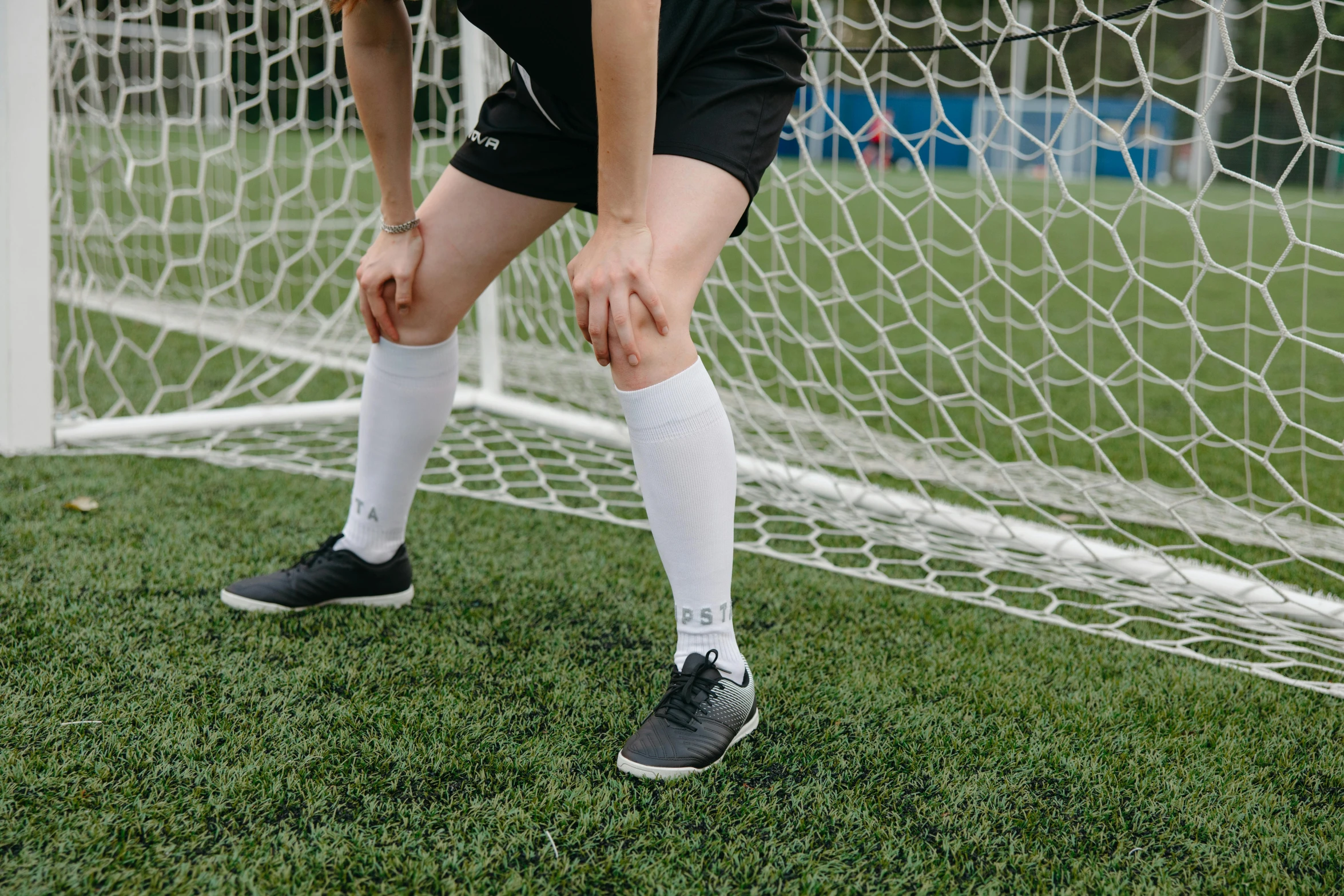 a person leaning over while playing soccer on grass