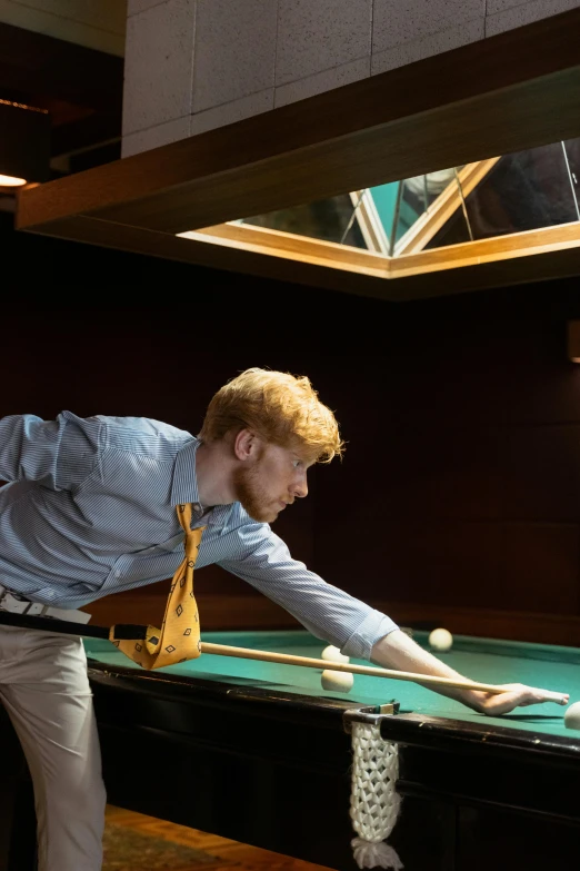 a man standing at a pool table playing a game of pool