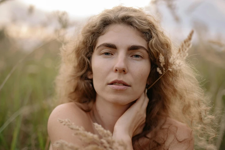 a woman standing in a field with her hair pulled back and eyes closed