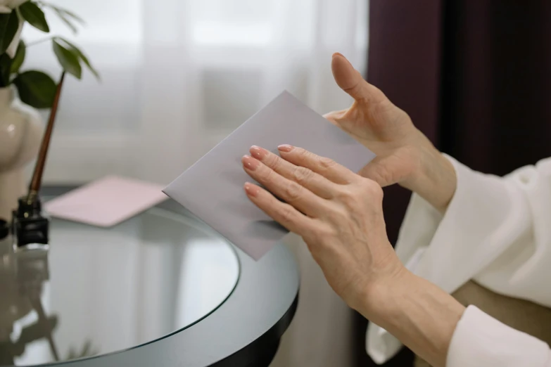 a person sitting at a glass table holding a book