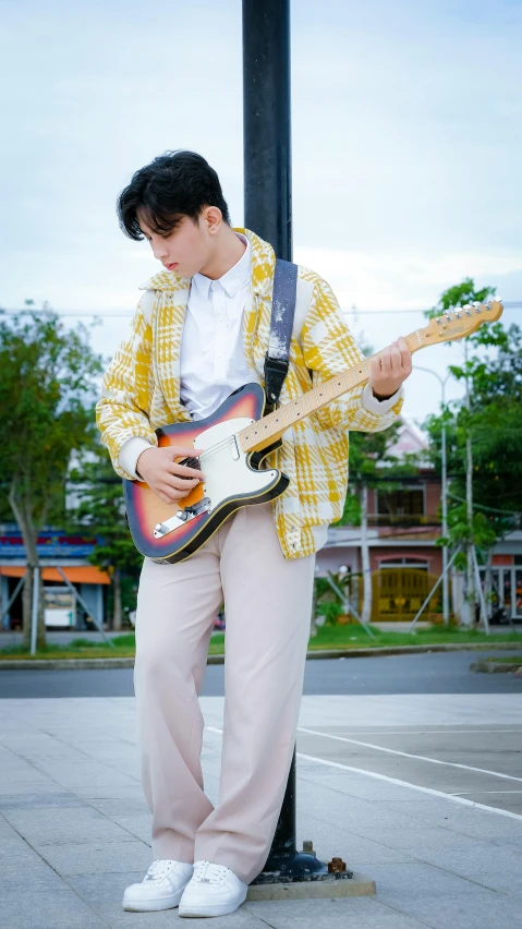 the young man is playing his guitar on the side walk