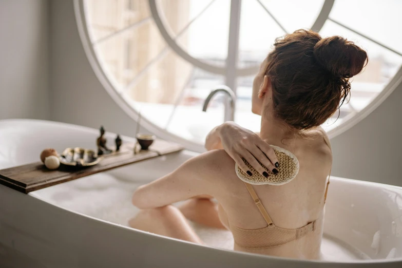 woman sitting in bathtub with window view in background