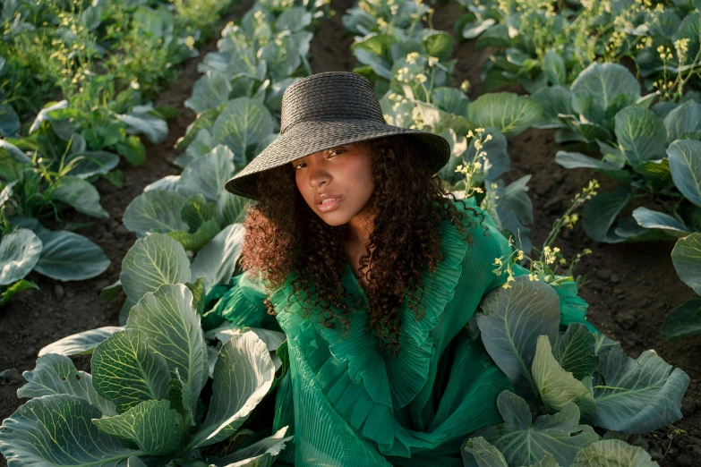 a woman kneeling down in a field holding some crops