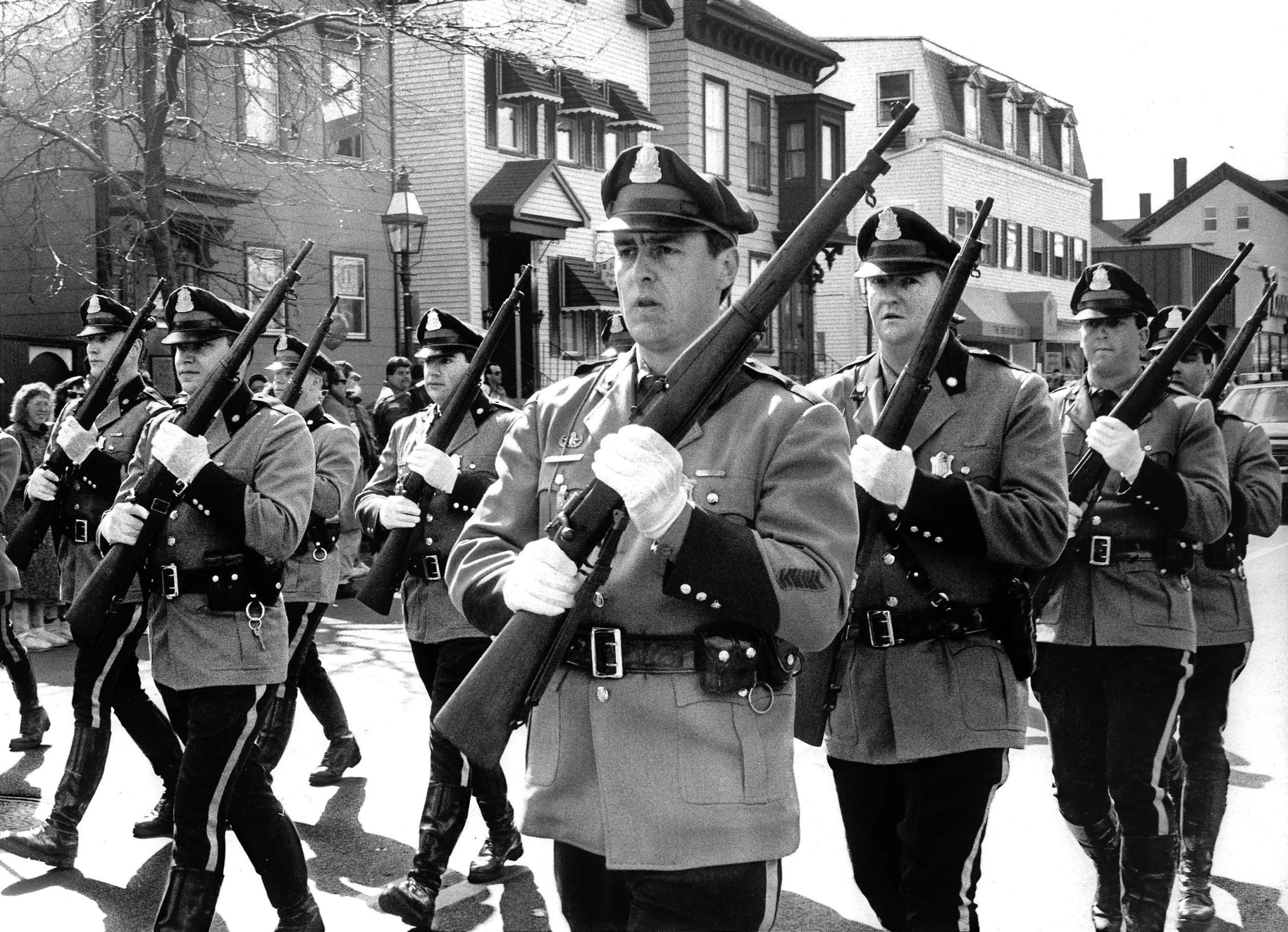 two military women with rifle and gun are marching down the street