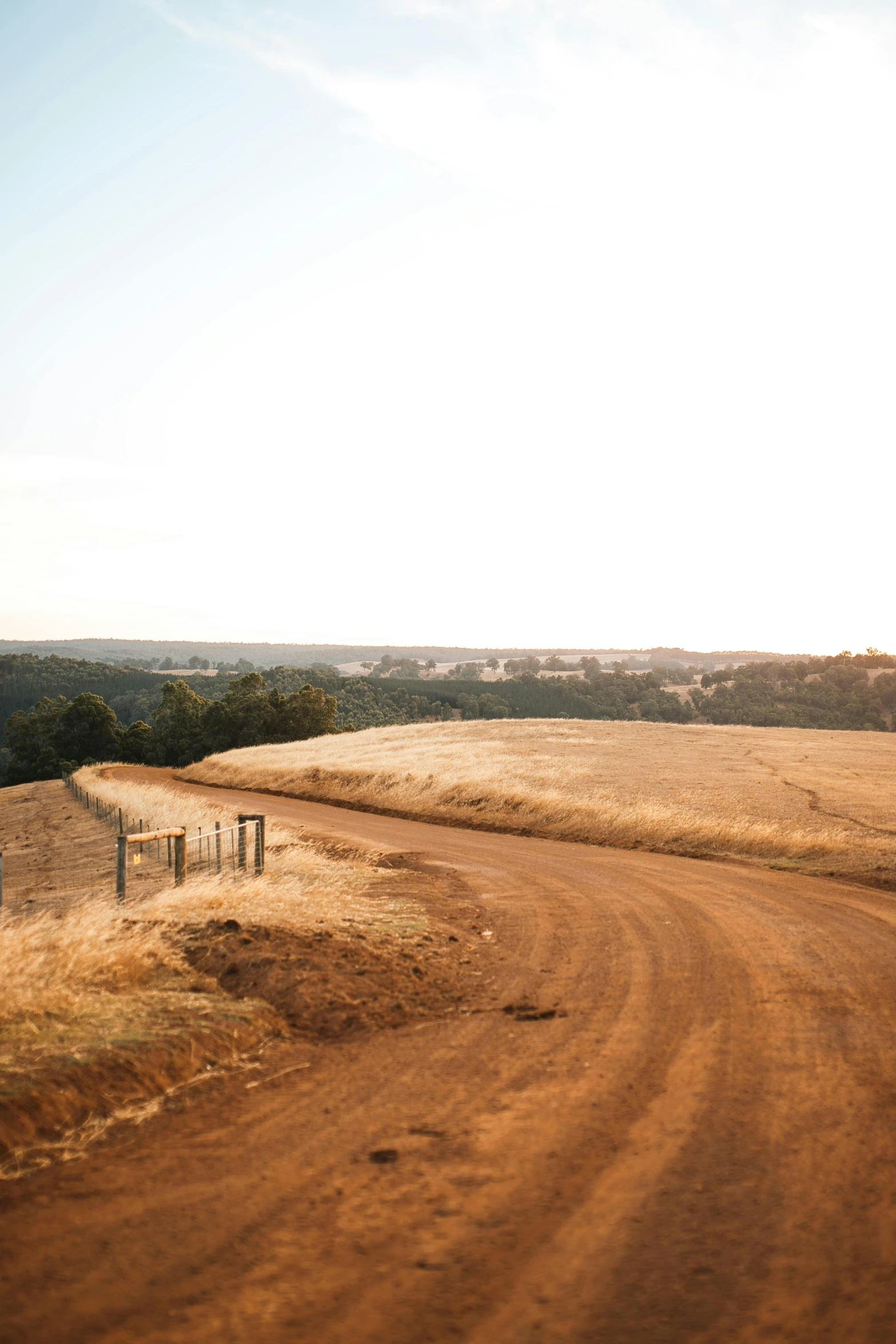 the dirt road curves into a rural area