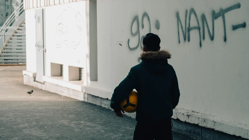a person holding a soccer ball while standing in front of a wall