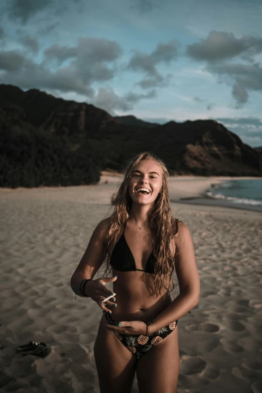 a woman wearing a black bikini standing on a beach