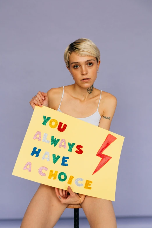 a person sitting on a chair holding a sign with words and writing