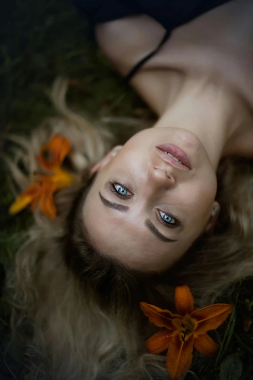 a woman laying on the grass and flowers behind her